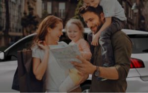 Happy family with shopping bags, looking at map near car.