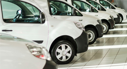 Row of white cargo vans in a showroom.