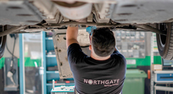 Mechanic working underneath a car in Northgate Talleres garage.